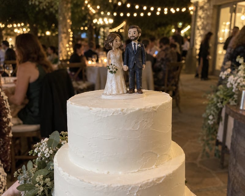 A mini me cake topper of a bride and groom on a white wedding cake
